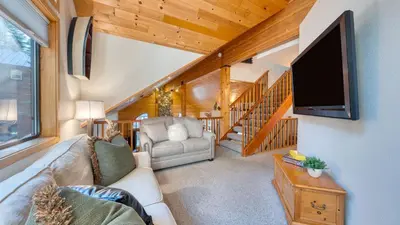a living room with a couch and a flat screen tv at Cozy Escape w Hot Tub Deck Access to Tahoe Donner Skiing Alpenglow Chalet by AvantStay in Truckee