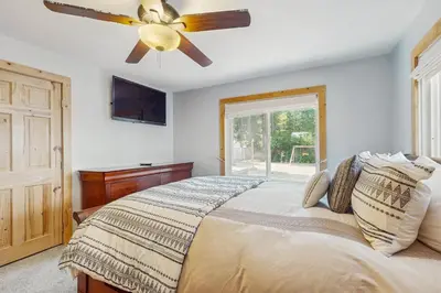 a bedroom with a bed with a ceiling fan and a window at Tata Cabin in South Lake Tahoe