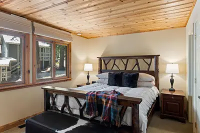 a bedroom with a wooden bed and two windows at Luxury 4BR Retreat Near Northstar Sleeps 10 in Tahoe Vista