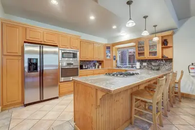 a kitchen with wooden cabinets and a stainless steel refrigerator at TaHaus Hot Tub Pool Table Dog Friendly in South Lake Tahoe