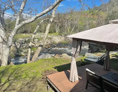 a wooden deck with a gazebo and a river at Riverfront with EV charger - Sequoia River Cottage in Three Rivers