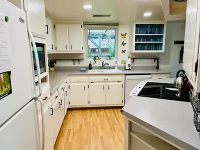 a kitchen with white cabinets and a white refrigerator at Riverfront with EV charger - Sequoia River Cottage in Three Rivers
