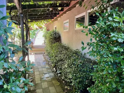 a building with a hedge of plants and a walkway at Riverfront with EV charger - Sequoia River Cottage in Three Rivers