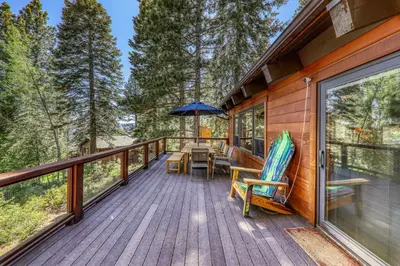 a deck with a table and chairs and an umbrella at Twin Hollow at Dollar Point by Tahoe Getaways - 5BR w Game Room & Hot Tub in Tahoe City