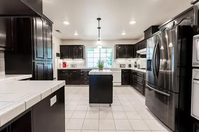 a kitchen with black cabinets and a black refrigerator at Yosemite and Bass lake I Hot tub I Game room I Sleeps 13 in Oakhurst