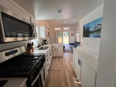 a kitchen with white cabinets and a stove top oven at Tiny Blanca at Yosemite Gateway in Groveland