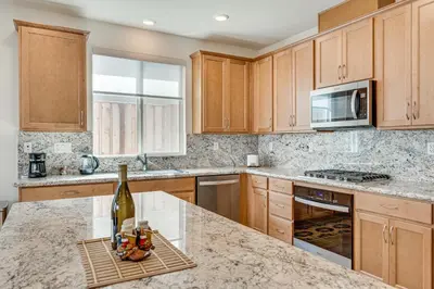 a kitchen with wooden cabinets and a bottle of wine at Newly Built Home with Patio 4 Mi to Dtwn Hollister in Hollister