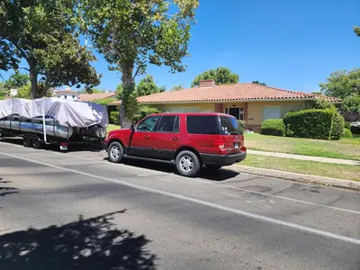 a red suv parked next to a truck with a trailer at Peaceful family home in Fresno