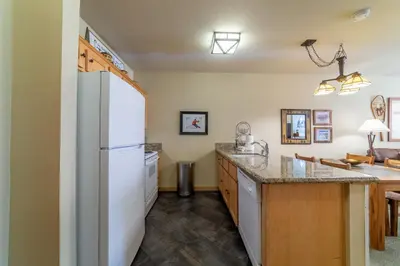 a kitchen with a white refrigerator and a counter at Ski in/Out 1B/1BA w/ View - Pool, Jacuzzi, Parking in Mammoth Lakes