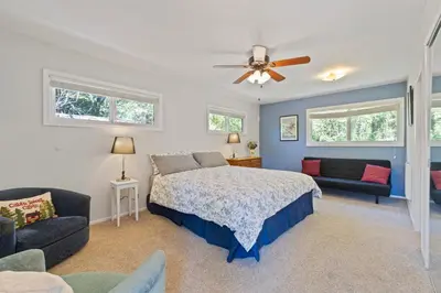 a bedroom with a bed and a couch and a fan at Red Cabin in Twain Harte - King bed in Twain Harte