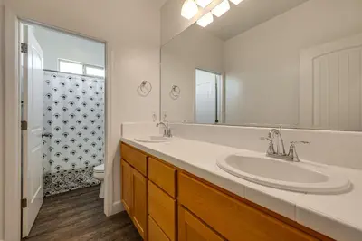 a bathroom with two sinks and a mirror at 1 Mi to Golf! Spacious and Modern Home in Dinuba in Dinuba