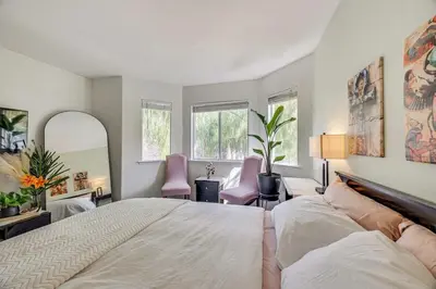 a bedroom with a large bed and two pink chairs at Rudraksha-5BR Luxury,3Bath, NE Fresno, Shopping, Dining, Medical, Tourist Attractions in Fresno