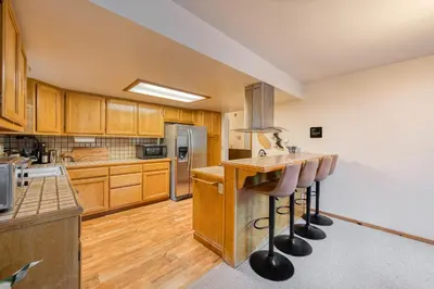 a kitchen with wooden cabinets and a counter with bar stools at Hearthlight Cabin at Tahoe Donner by Tahoe Getaways - Pet-Friendly 3BR w Guest Suite in Truckee
