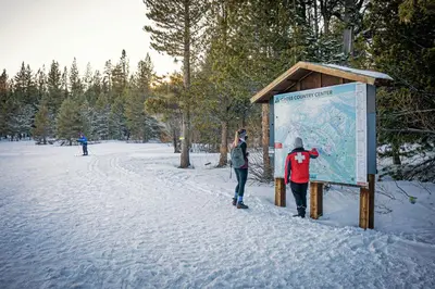 a man and a woman standing next to a sign in the snow at Hearthlight Cabin at Tahoe Donner by Tahoe Getaways - Pet-Friendly 3BR w Guest Suite in Truckee