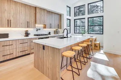 a kitchen with wooden cabinets and a island with bar stools at 4 Mi to Soda Springs Resort Hot Tub Hideaway! in Soda Springs