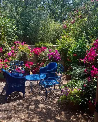 a table and chairs in a garden with flowers at Heidi's Artistic Abode in Three Rivers