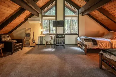a bedroom with a bed and a desk and windows at Woodland Chalet Retreat with Hot Tub in Arnold
