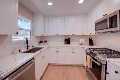 a kitchen with white cabinets and a stove top oven at Folsom Old Town Escape • Cozy Cottage + Library in Folsom