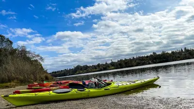 a yellow kayak sitting on the shore of a river at Folsom Old Town Escape • Cozy Cottage + Library in Folsom