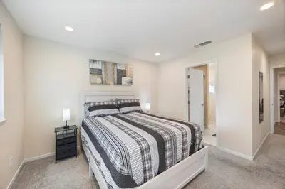 a bedroom with a bed in a white room at Cozy Nest Across the street from UC Davis Sacramento in Sacramento