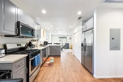 a kitchen with stainless steel appliances and wooden floors at Cozy Nest Across the street from UC Davis Sacramento in Sacramento