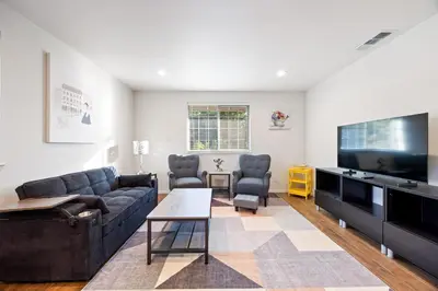 a living room with a couch and a flat screen tv at Cozy Nest Across the street from UC Davis Sacramento in Sacramento