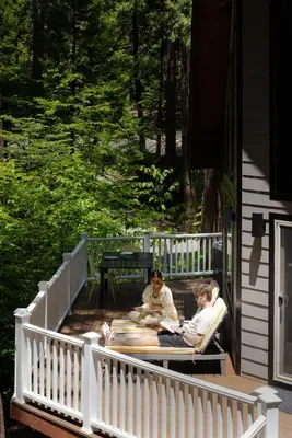 two people sitting on the porch of a house at A-Frame Cabin - Sauna, Hot Tub, Fire Pit, Projector in Arnold