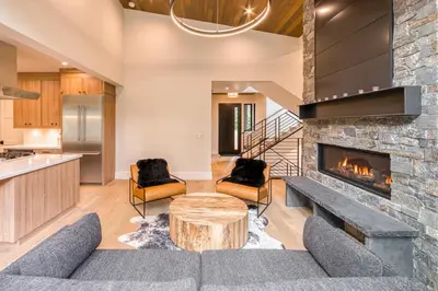 a living room with a fireplace and a table at Shining Creek at Alpine Meadows by Tahoe Getaways - 4 BR w Creek Views, Hot Tub & Ski Shuttle! in Alpine Meadows