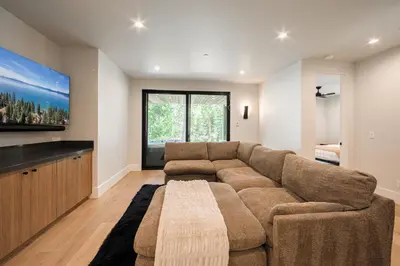 a living room with a couch and a flat screen tv at Shining Creek at Alpine Meadows by Tahoe Getaways - 4 BR w Creek Views, Hot Tub & Ski Shuttle! in Alpine Meadows