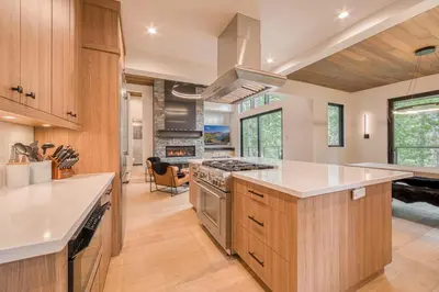 a kitchen with wooden cabinets and a stove top oven at Shining Creek at Alpine Meadows by Tahoe Getaways - 4 BR w Creek Views, Hot Tub & Ski Shuttle! in Alpine Meadows