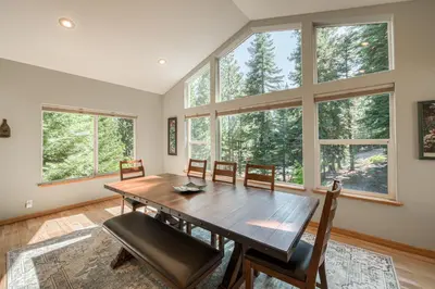 a dining room with a table and chairs and windows at Emerald Lodge at Tahoe Park by Tahoe Getaways - 4BR w HOA Beach & Air Conditioning in Tahoe City