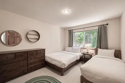 a bedroom with two beds and a mirror and a window at Emerald Lodge at Tahoe Park by Tahoe Getaways - 4BR w HOA Beach & Air Conditioning in Tahoe City