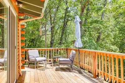 a porch with a table and chairs and an umbrella at Community Lake Access Peaceful Cabin in Sonora! in Sonora