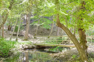 a wooden bridge over a stream in a forest at Community Lake Access Peaceful Cabin in Sonora! in Sonora