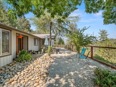 a patio with a blue chair in front of a house at Serene Views with Hot Tub, BBQ, Fire Pit, Game Room in Oakhurst