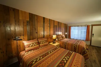 two beds in a hotel room with wooden walls at Tamarack Lodge Motel in Tahoe City