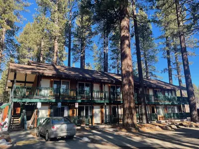 a house in the woods with a car parked in front at Tamarack Lodge Motel in Tahoe City