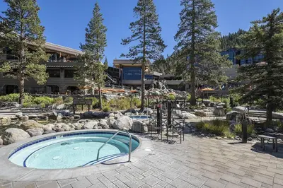 a swimming pool in a garden with rocks and a building at Community Perks! Everline Resort and Spa Retreat in Olympic Valley