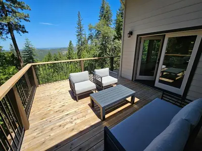 a wooden deck with two chairs and a table at Cedar Rock Cabin in Mi-Wuk Village