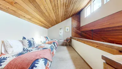 two beds in a room with a wooden ceiling at Mammoth Sierra Townhomes #25 condo in Mammoth Lakes