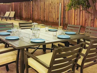 a wooden table with plates and glasses on it at Old Fig House - Historic Fig Garden Neighborhood in Fresno