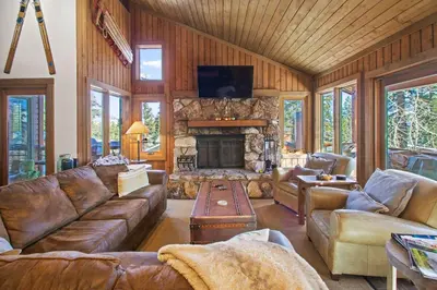 a living room with leather furniture and a stone fireplace at Corner 3BD with Loft! Walk to Canyon and The Village! in Mammoth Lakes