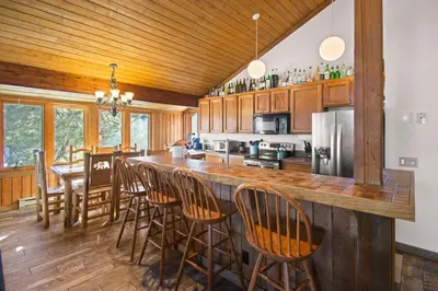 a kitchen with a bar with chairs and a table at Corner 3BD with Loft! Walk to Canyon and The Village! in Mammoth Lakes