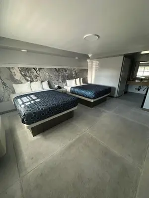 a bedroom with two beds and a stone wall at HomeTown Inn in Los Banos