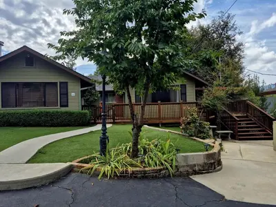 a house with a tree in the front yard at Cozy Cabin by Bass Lake, with Boat Slip in Bass Lake