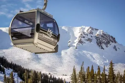 a ski lift with a snow covered mountain in the background at Sunshine Village 169 in Mammoth Lakes
