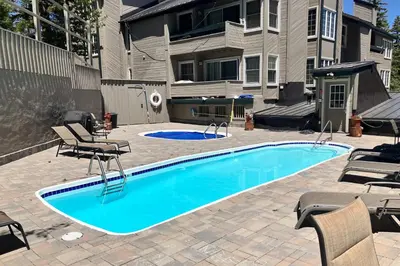 a swimming pool with chairs and a building at Sierra Megeve 3 in Mammoth Lakes