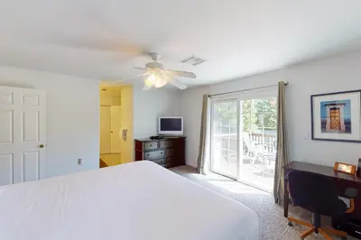 a bedroom with a white bed and a sliding glass door at Moler Lake House in Bass Lake