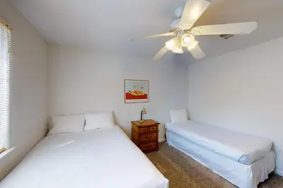 two beds in a room with a ceiling fan at Moler Lake House in Bass Lake