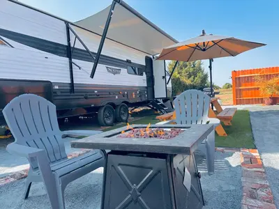 two chairs and a table with a fire pit and an rv at DDs Country Camper in Reedley